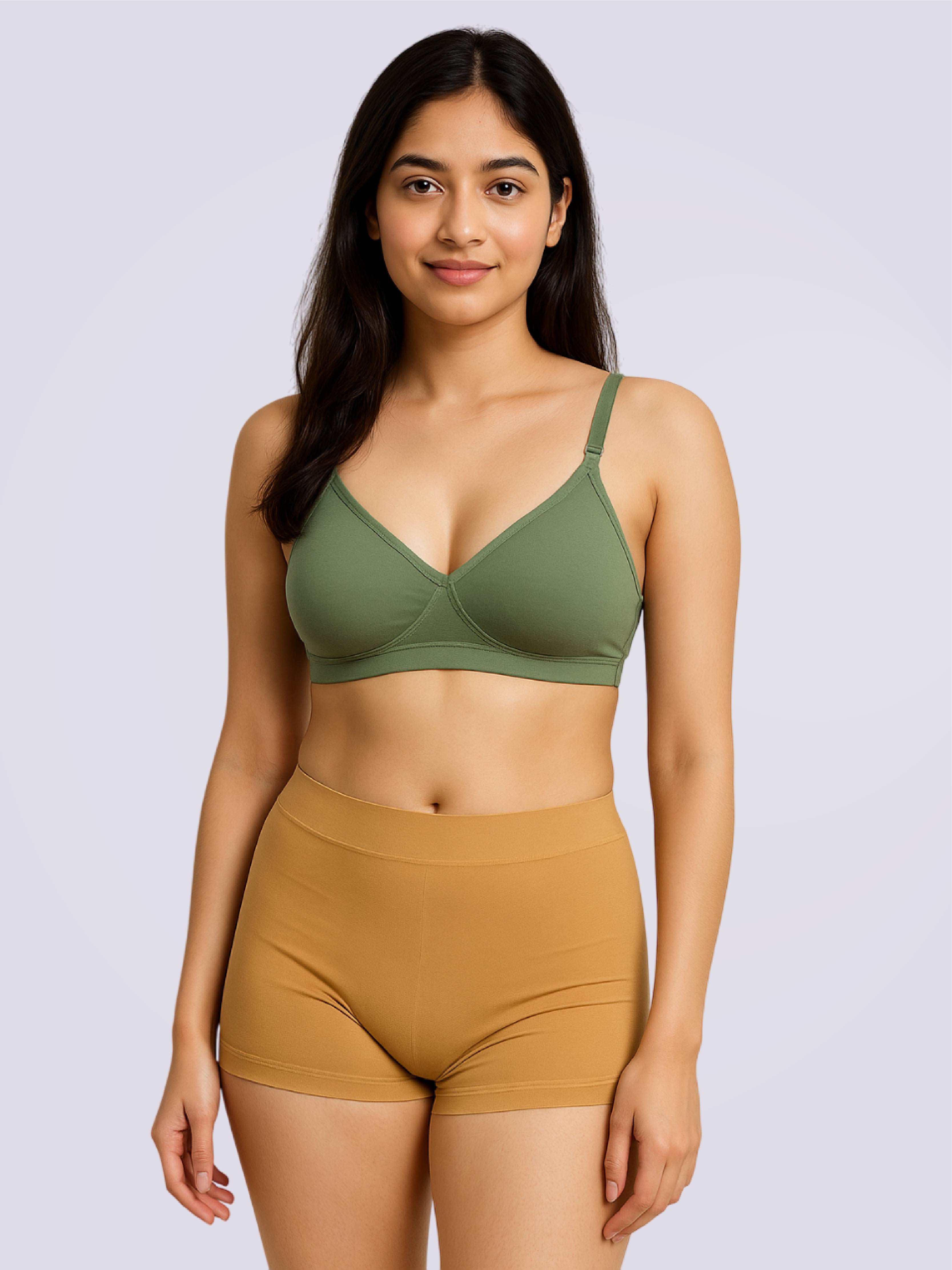 Woman wearing a olive green bra and mustard shorts on a light purple background